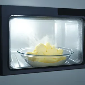 Whisked eggs in a microwave-safe bowl placed inside a microwave with the door slightly open.