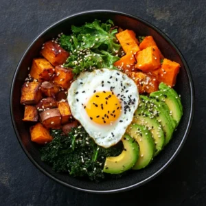 Customized Bibimbap bowl with avocado, roasted sweet potatoes, kale, sesame seeds, and a poached egg on a slate background.